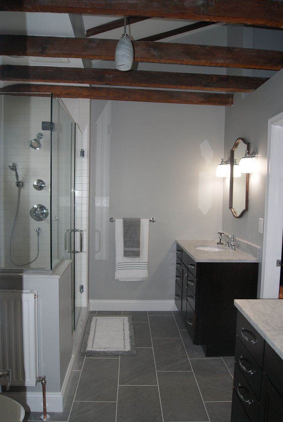 Bathroom with gray walls, dark wood vanity, glass shower, and exposed wooden beams.