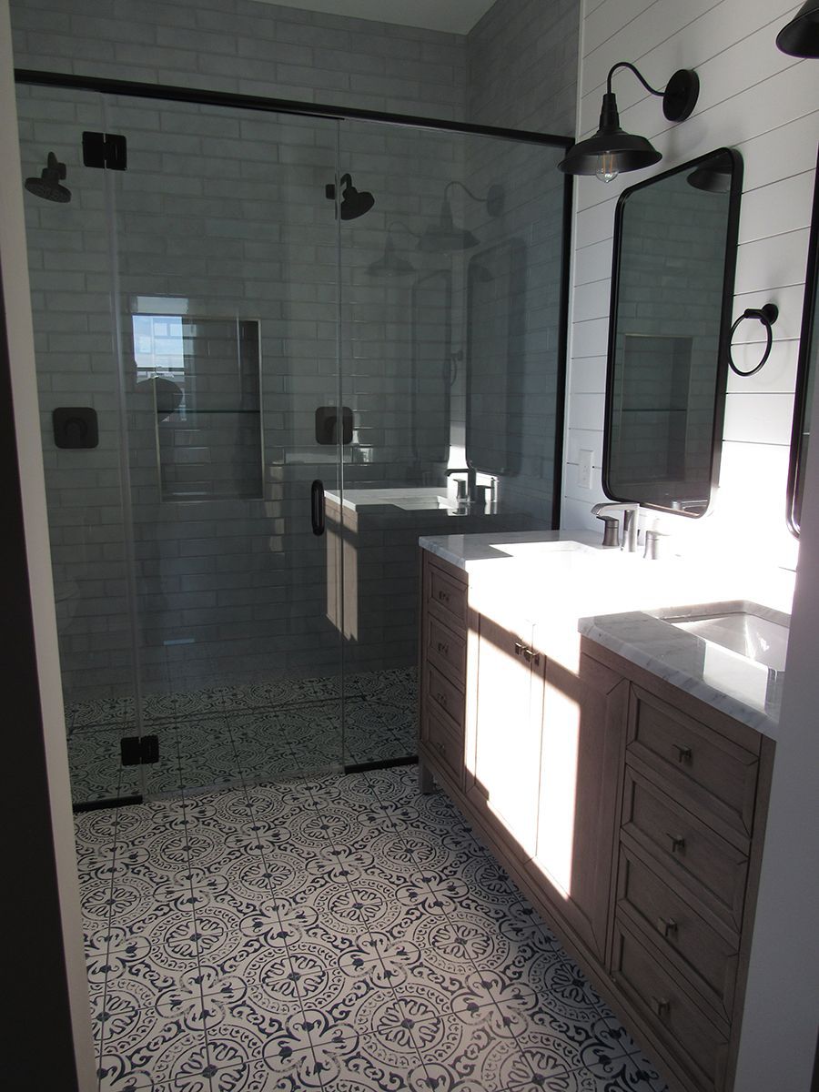 Bathroom with a glass shower, two sinks, and patterned tile flooring.