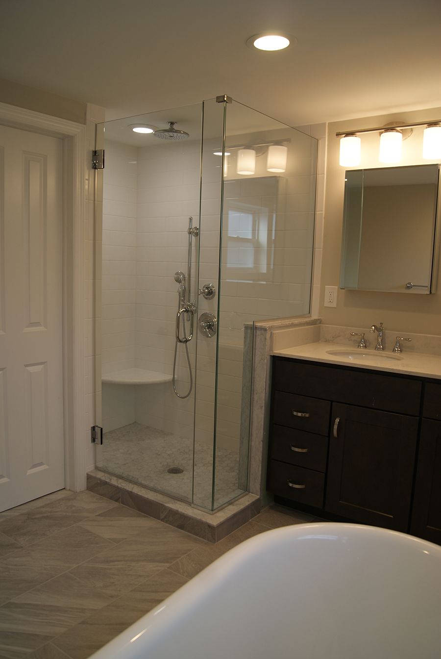 Modern bathroom with glass shower enclosure, vanity, and neutral tile flooring.