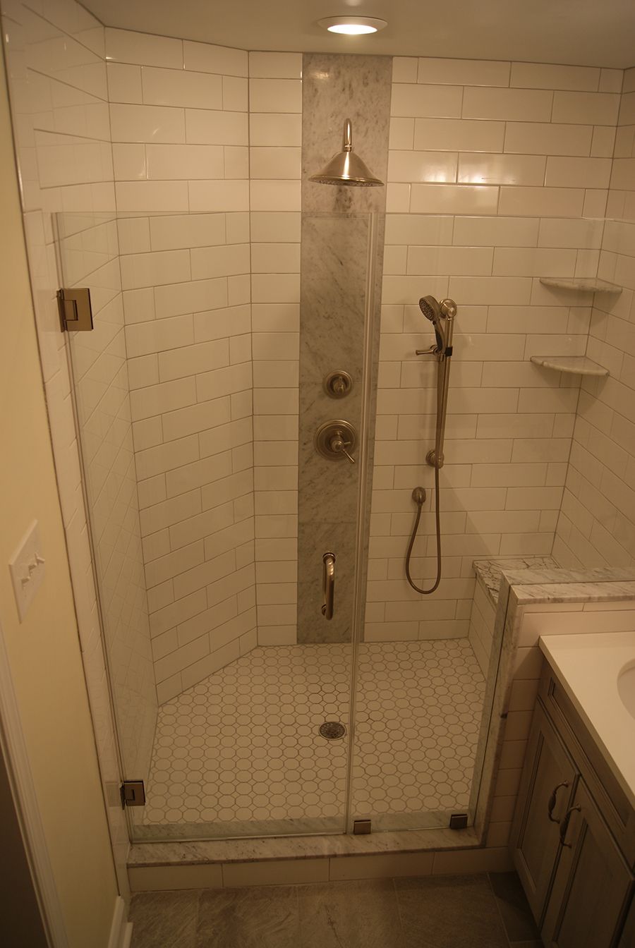 Modern bathroom with glass shower enclosure, white subway tile walls, and hexagon tile floor.