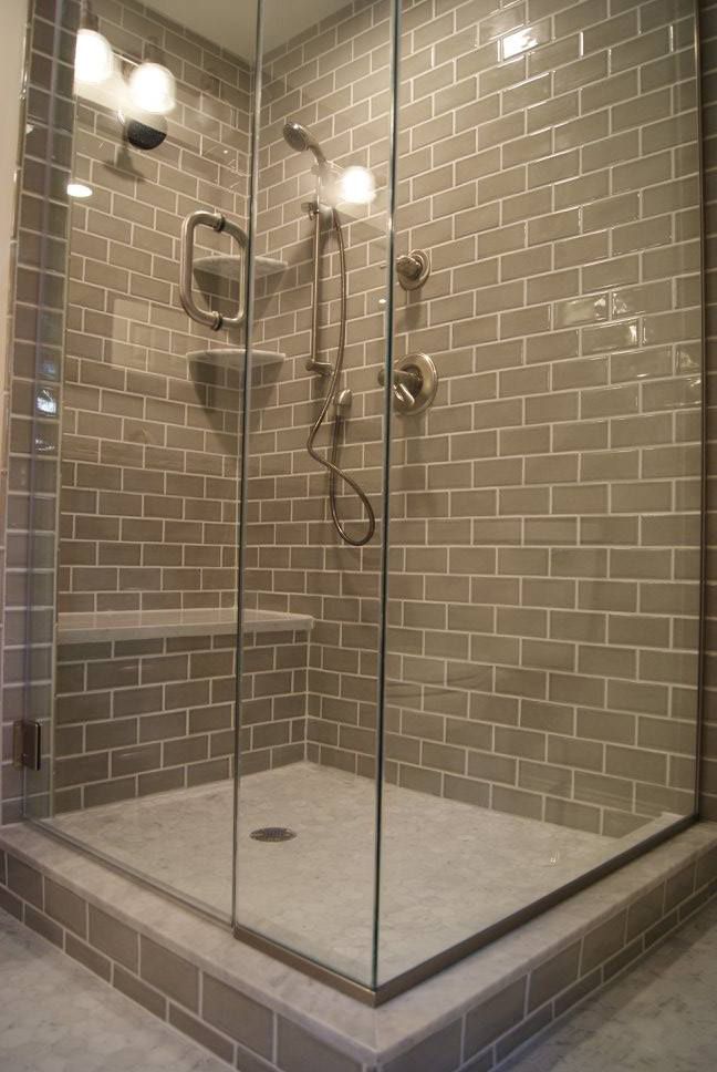 Corner shower with gray brick-like tile, clear glass doors, and a built-in bench.
