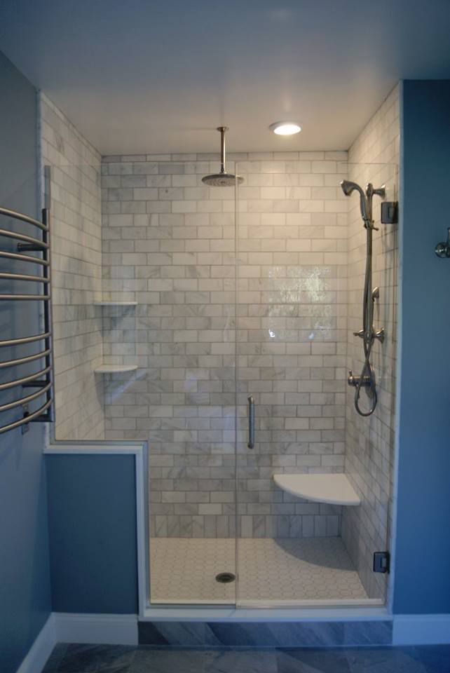 Modern bathroom shower with glass door, white tiled walls, and a built-in seat.