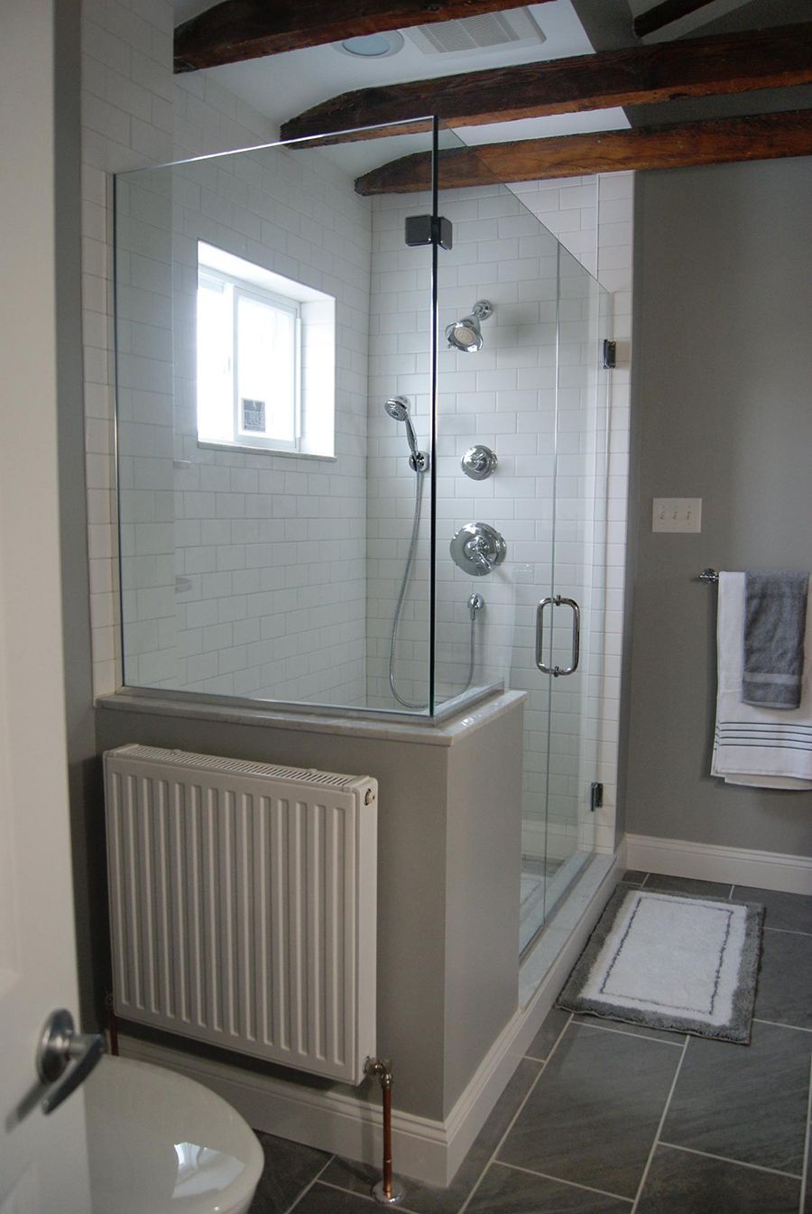 Modern bathroom with glass shower, gray walls, and white radiator.