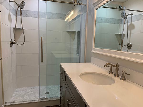 Bathroom with glass shower, white countertop with sink, and dark wood vanity.