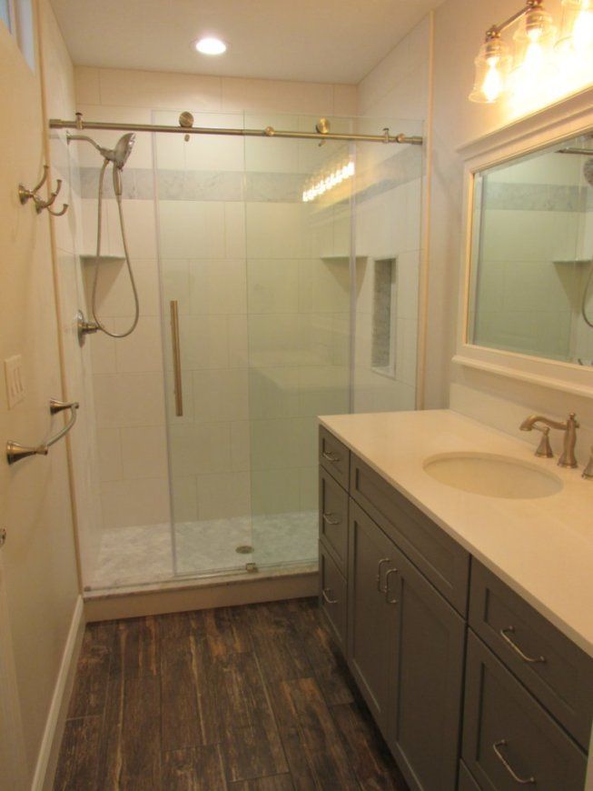 Modern bathroom with a glass shower, vanity, and wood-look flooring.