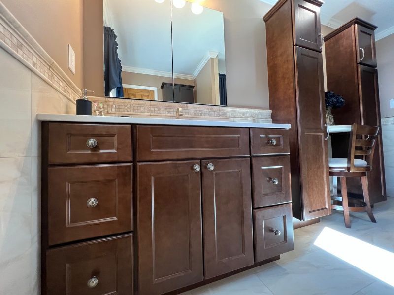 Bathroom with dark wood vanity, tall storage cabinets, and a chair.
