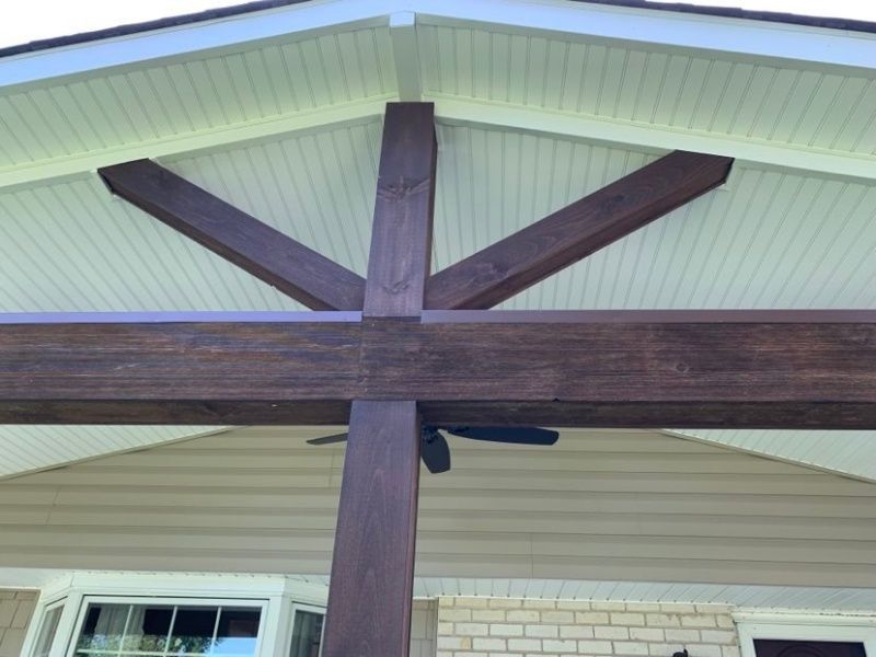 Dark stained wooden beams supporting a covered porch roof. A ceiling fan is visible.