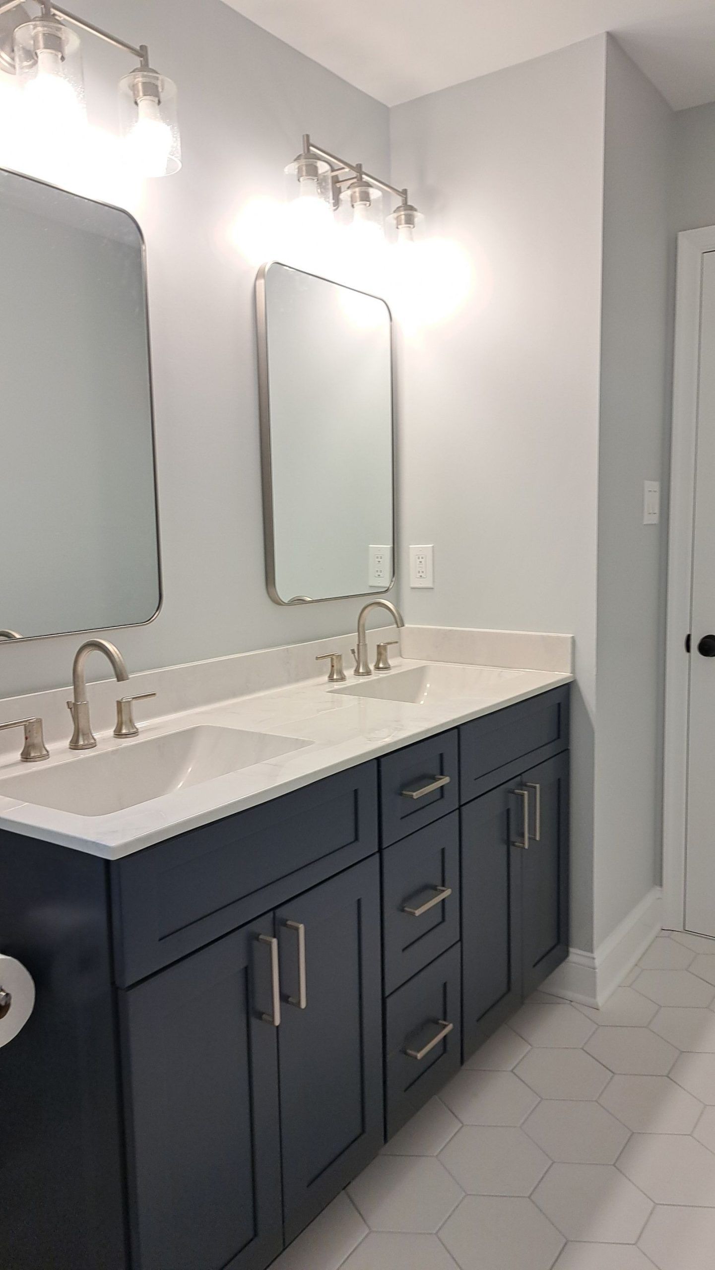 Bathroom with blue vanity, white countertop, silver fixtures, and hexagonal floor tiles.