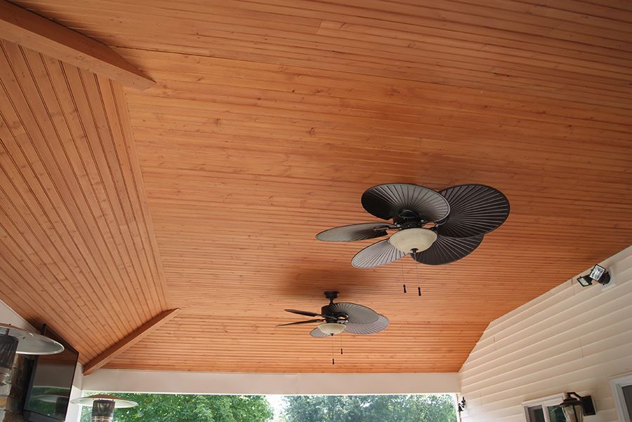 Wooden outdoor ceiling with two ceiling fans.