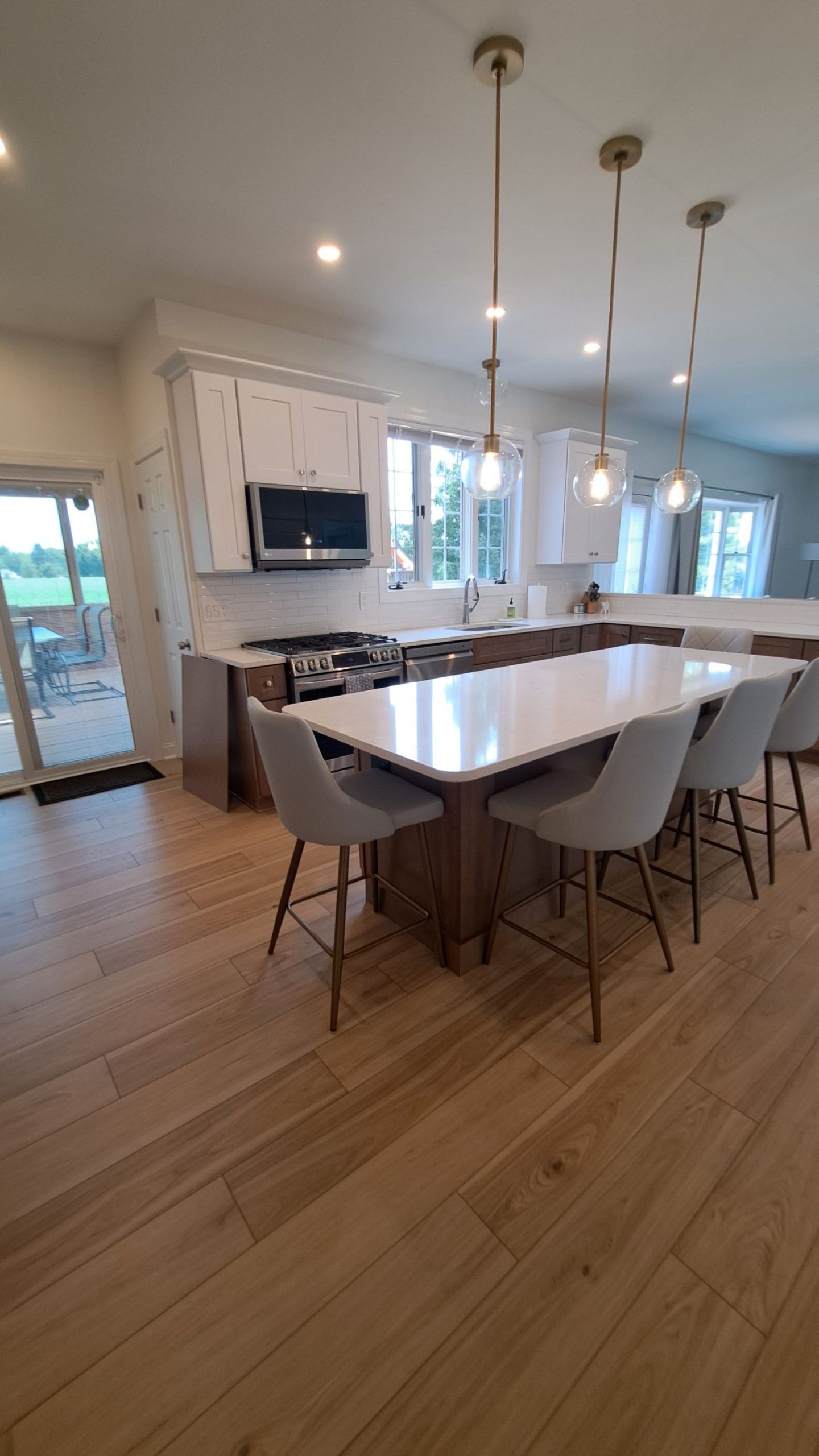 Modern kitchen with wooden floors, white countertops, and a large island with seating.