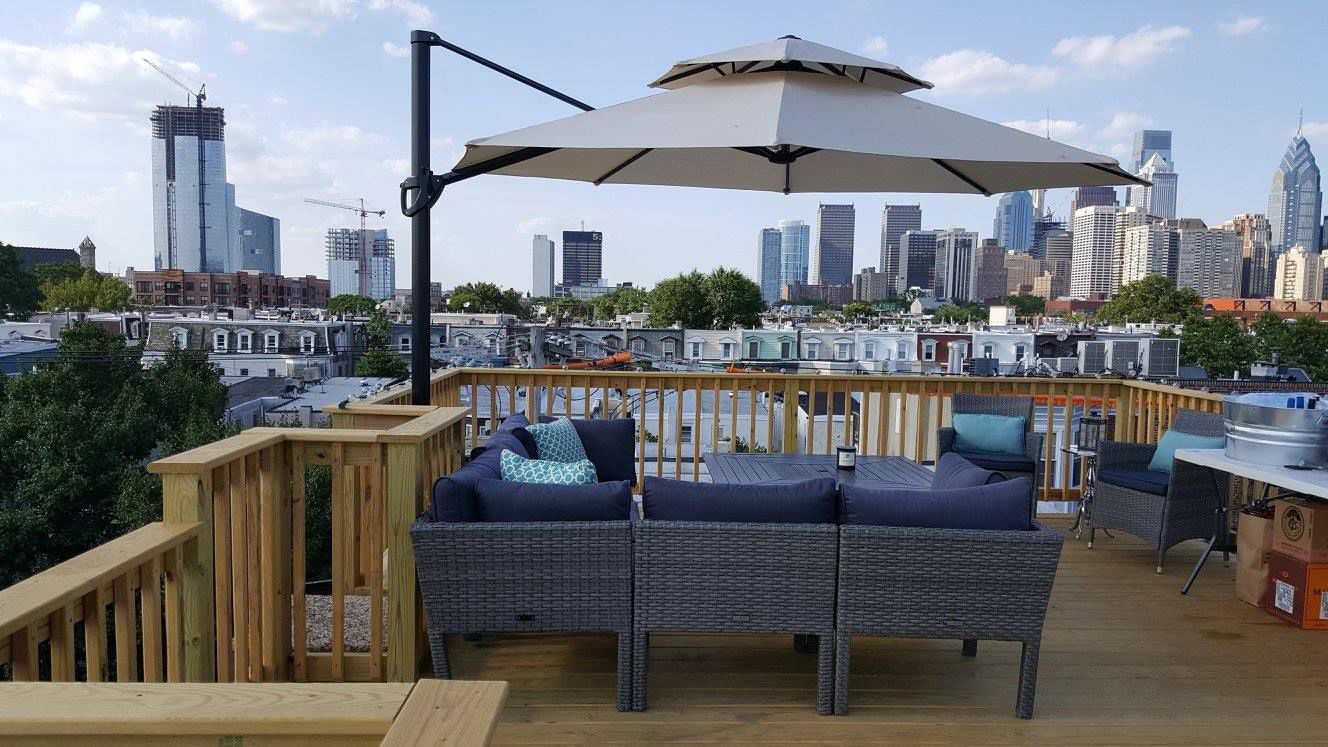Rooftop deck with patio furniture and umbrella overlooking a city skyline.
