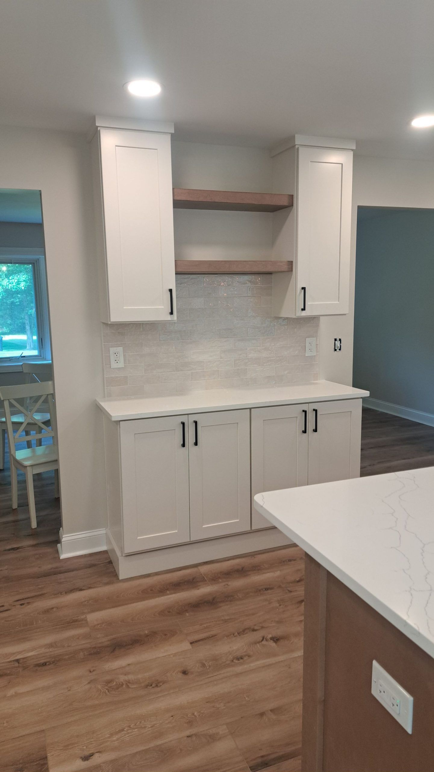 White kitchen cabinets with black hardware and wood shelves.