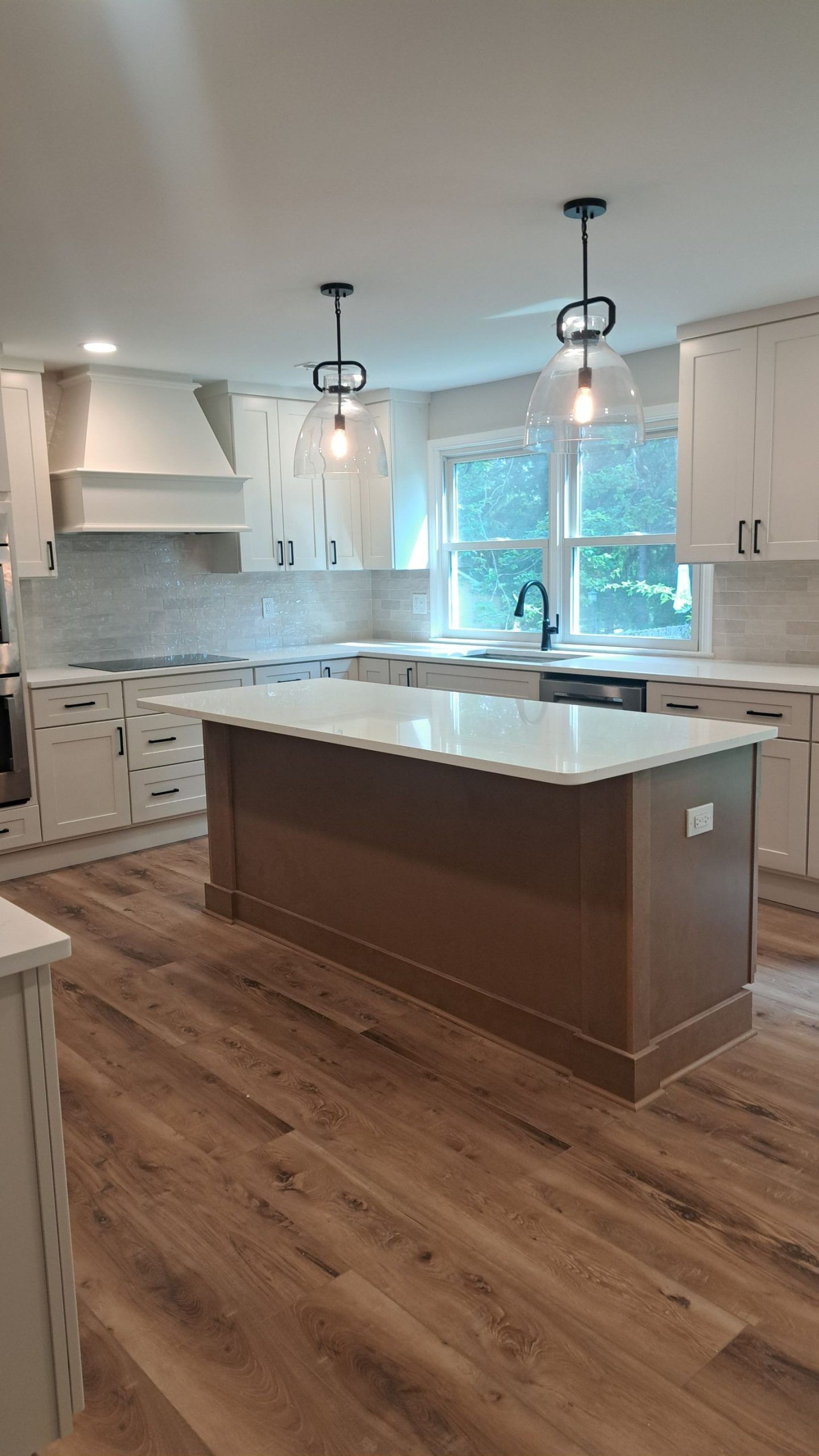 Modern kitchen with brown island and white countertops, cabinets, and backsplash.