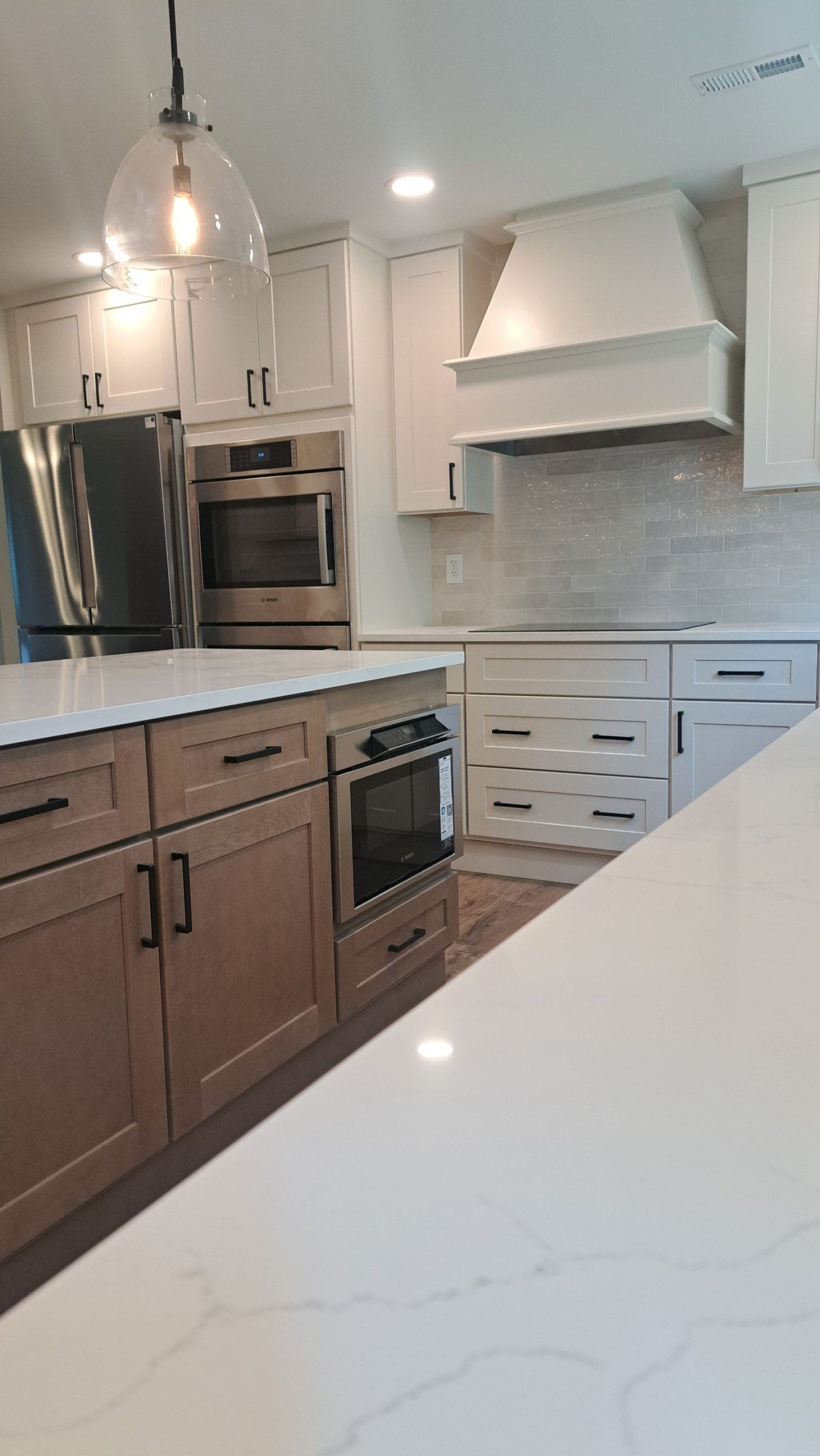 Modern kitchen with white countertops and cabinets, stainless steel appliances, and a central island.