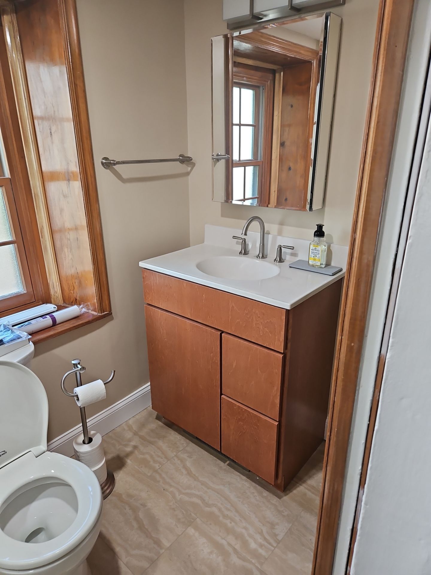 Bathroom with a toilet, vanity with sink, and a mirror.