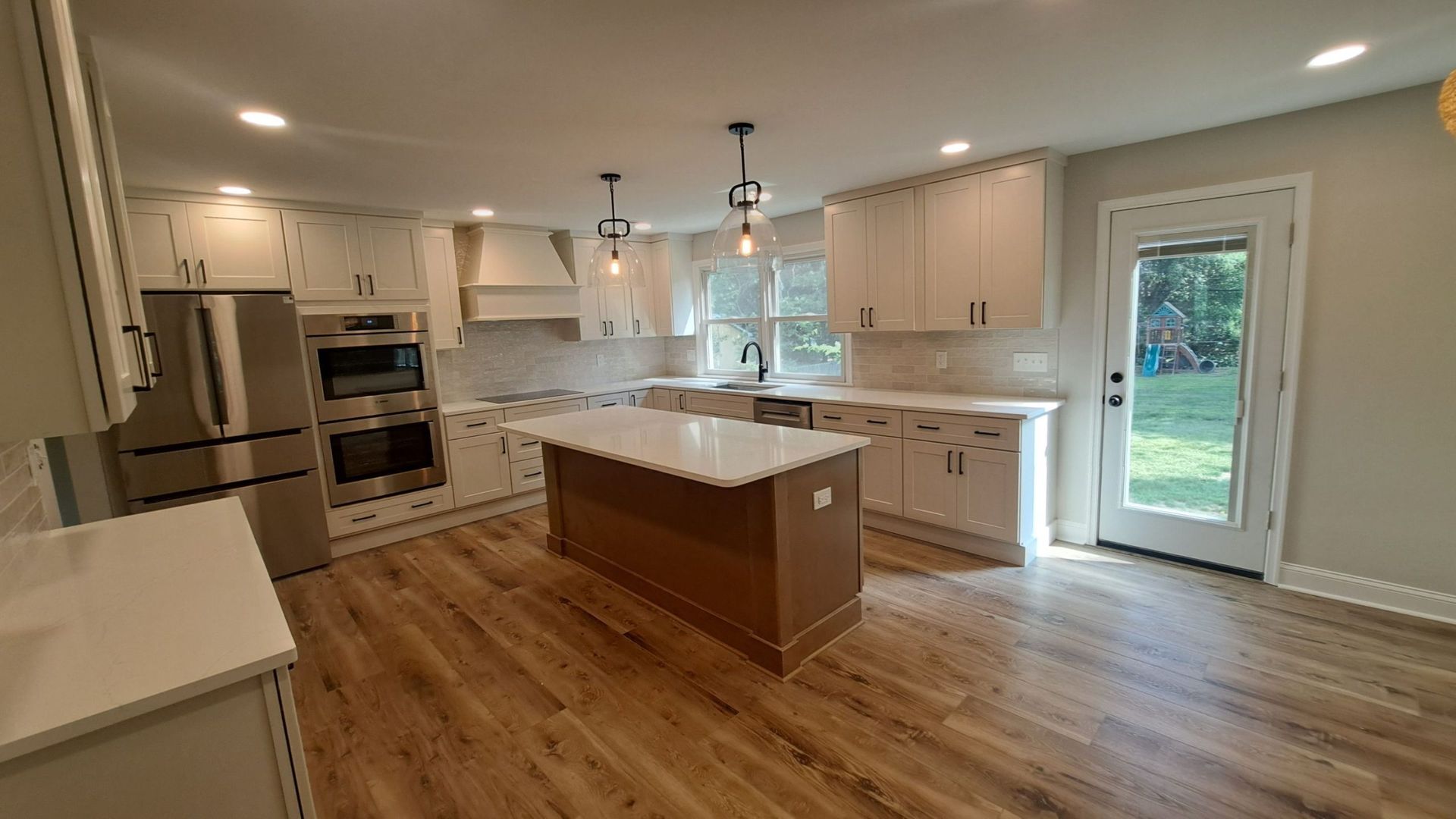 Modern kitchen with white cabinets, stainless steel appliances, and a wood island.