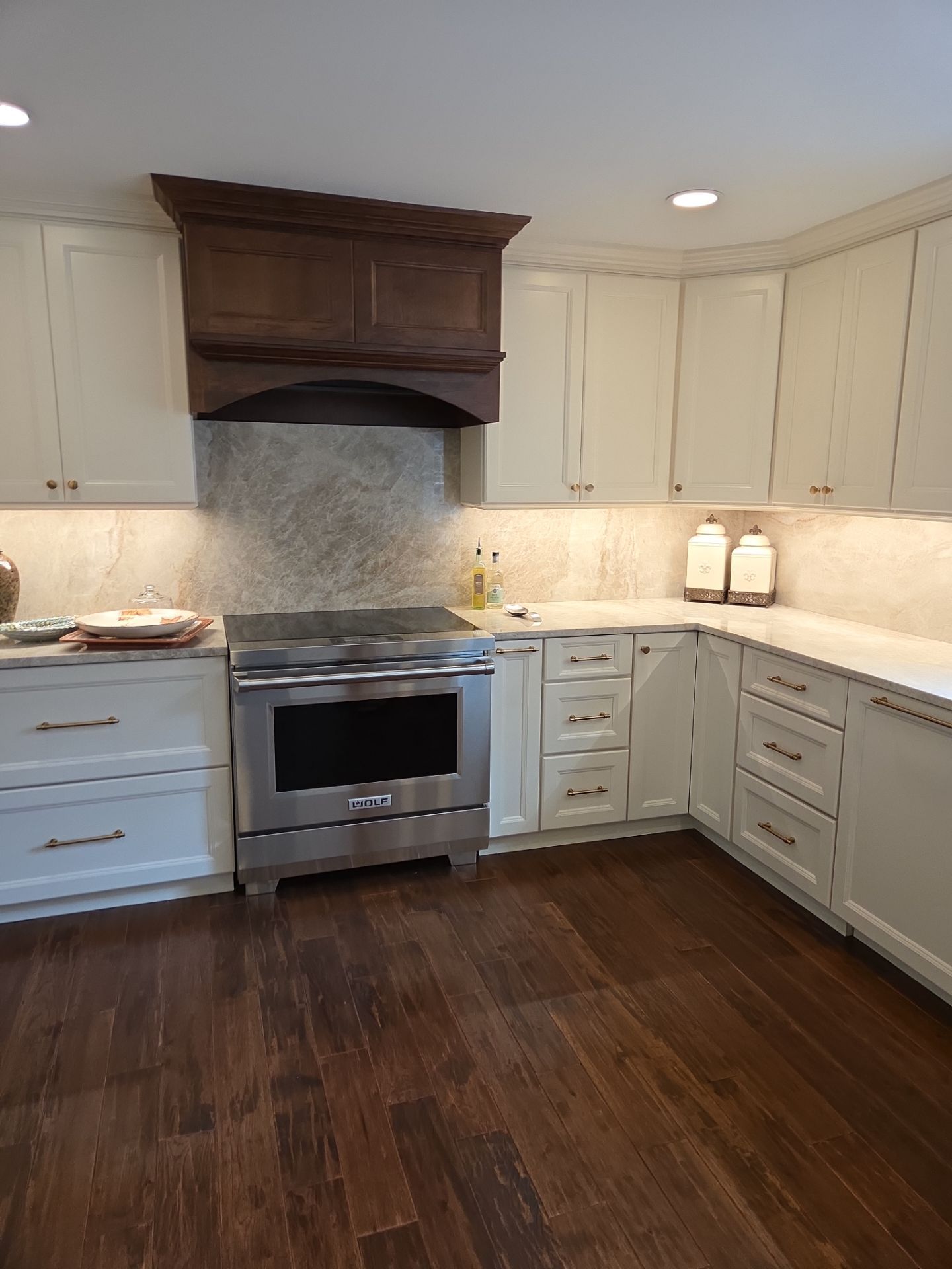 Kitchen with white cabinets, stainless steel stove, and dark wood floor.
