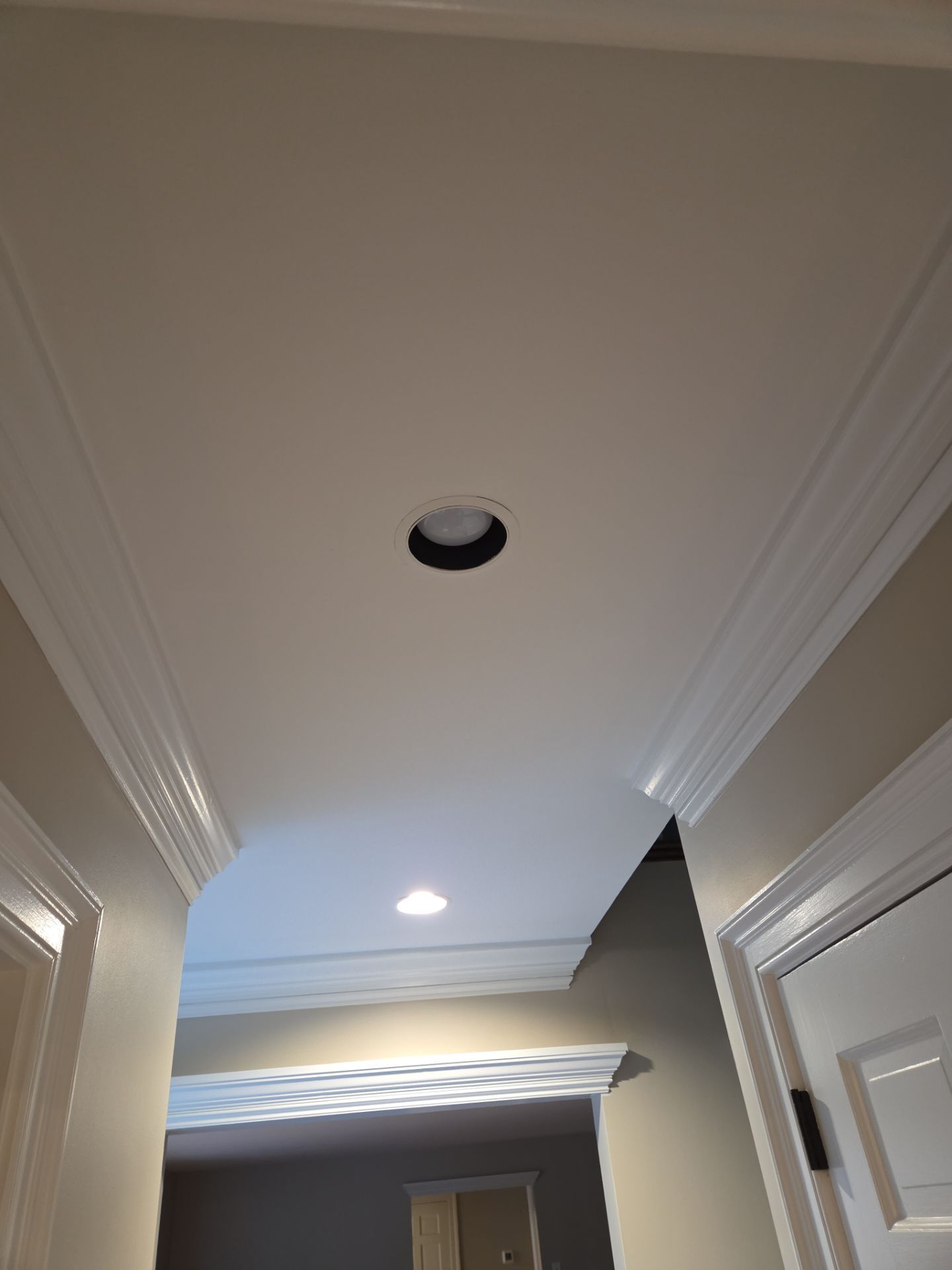 Ceiling with recessed lighting, crown molding, and doorways.