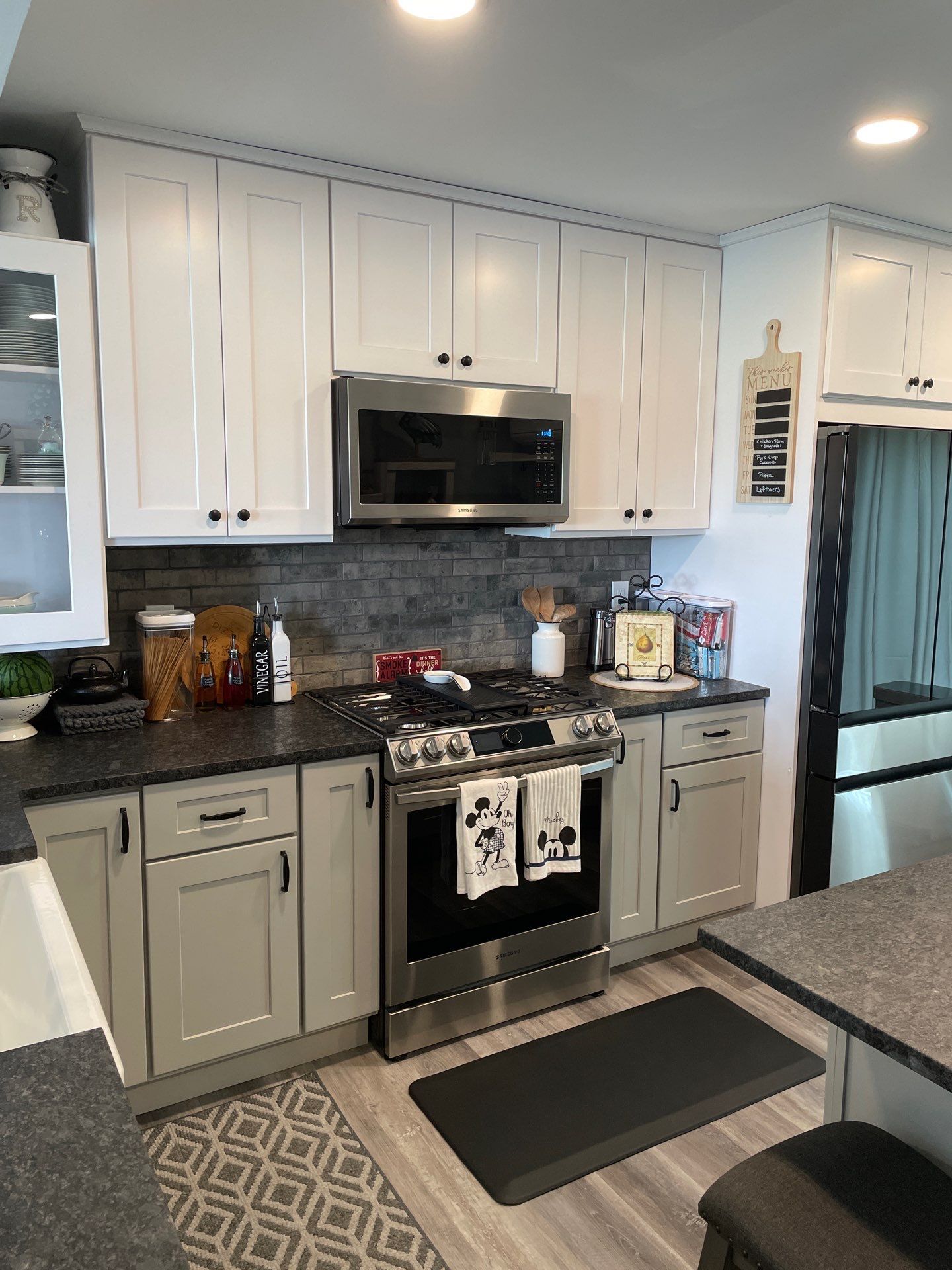 Kitchen with gray and white cabinets, stainless steel appliances, and dark countertops.