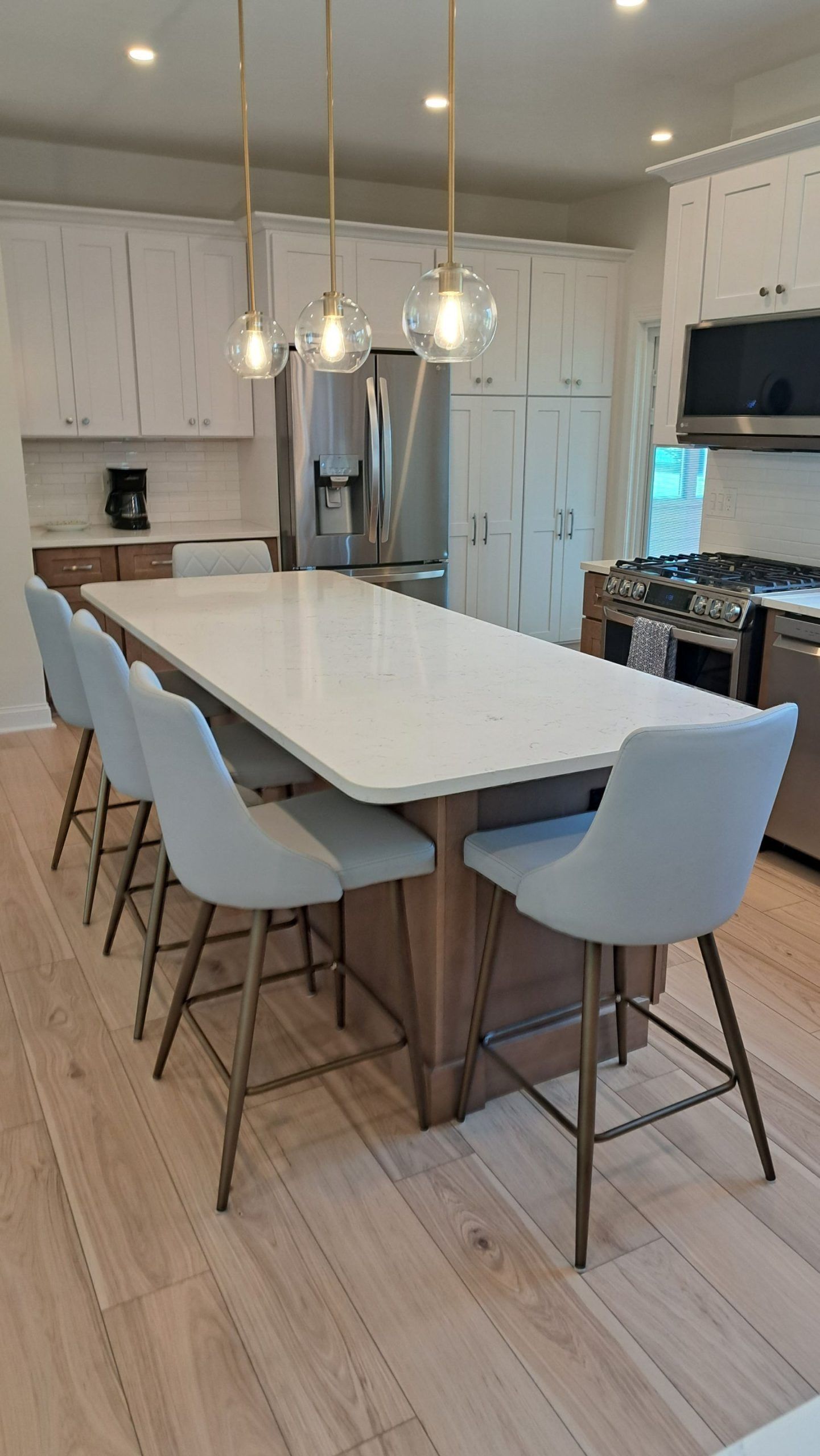 Spacious kitchen with large island, light blue bar stools, and pendant lights.