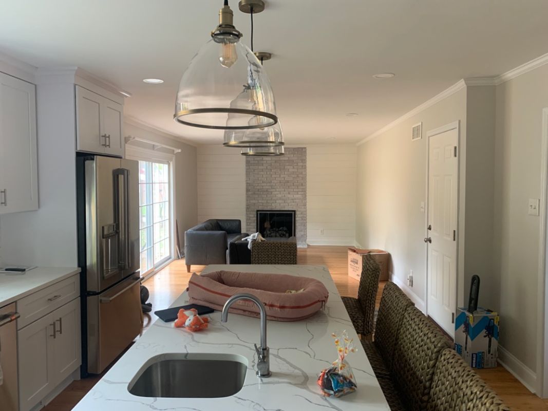 Open kitchen with island, facing living room with fireplace and sliding door to backyard.