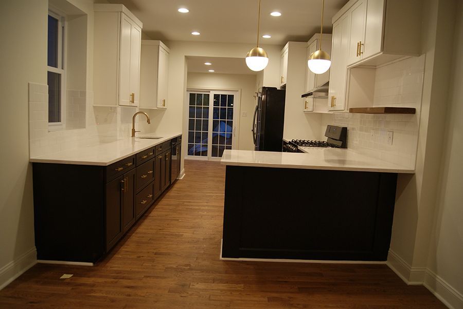 Modern kitchen with dark lower cabinets and white upper cabinets. Wooden floor.
