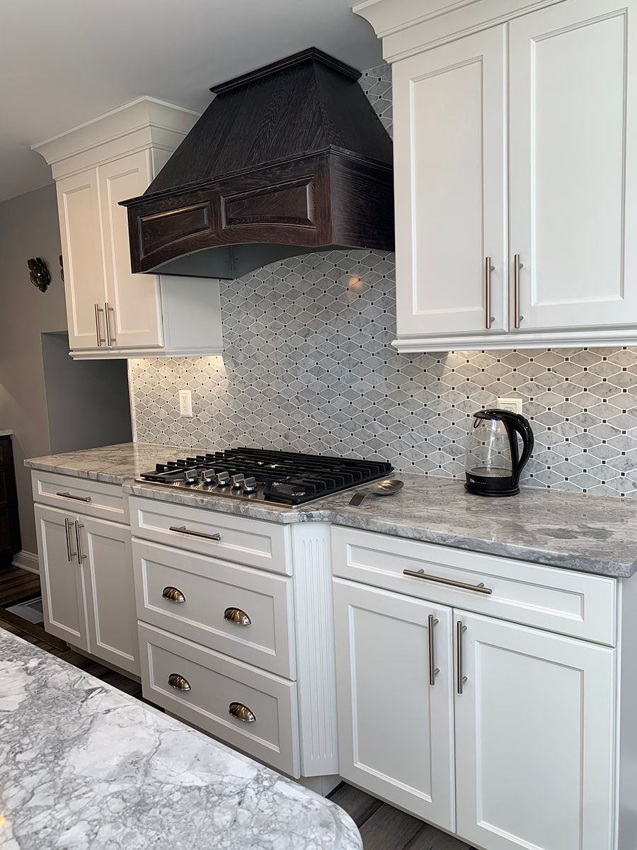 Kitchen with white cabinets, gray countertops, tiled backsplash, gas cooktop, and dark wood range hood.