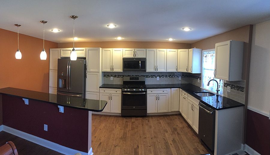 Modern kitchen with white cabinets, dark countertops, and stainless steel appliances.