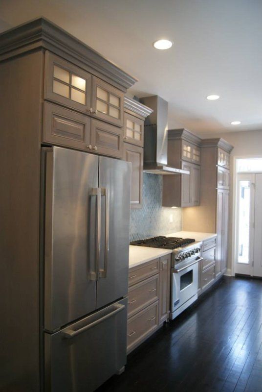 Modern kitchen with gray cabinets, stainless steel appliances, and dark wood floors.
