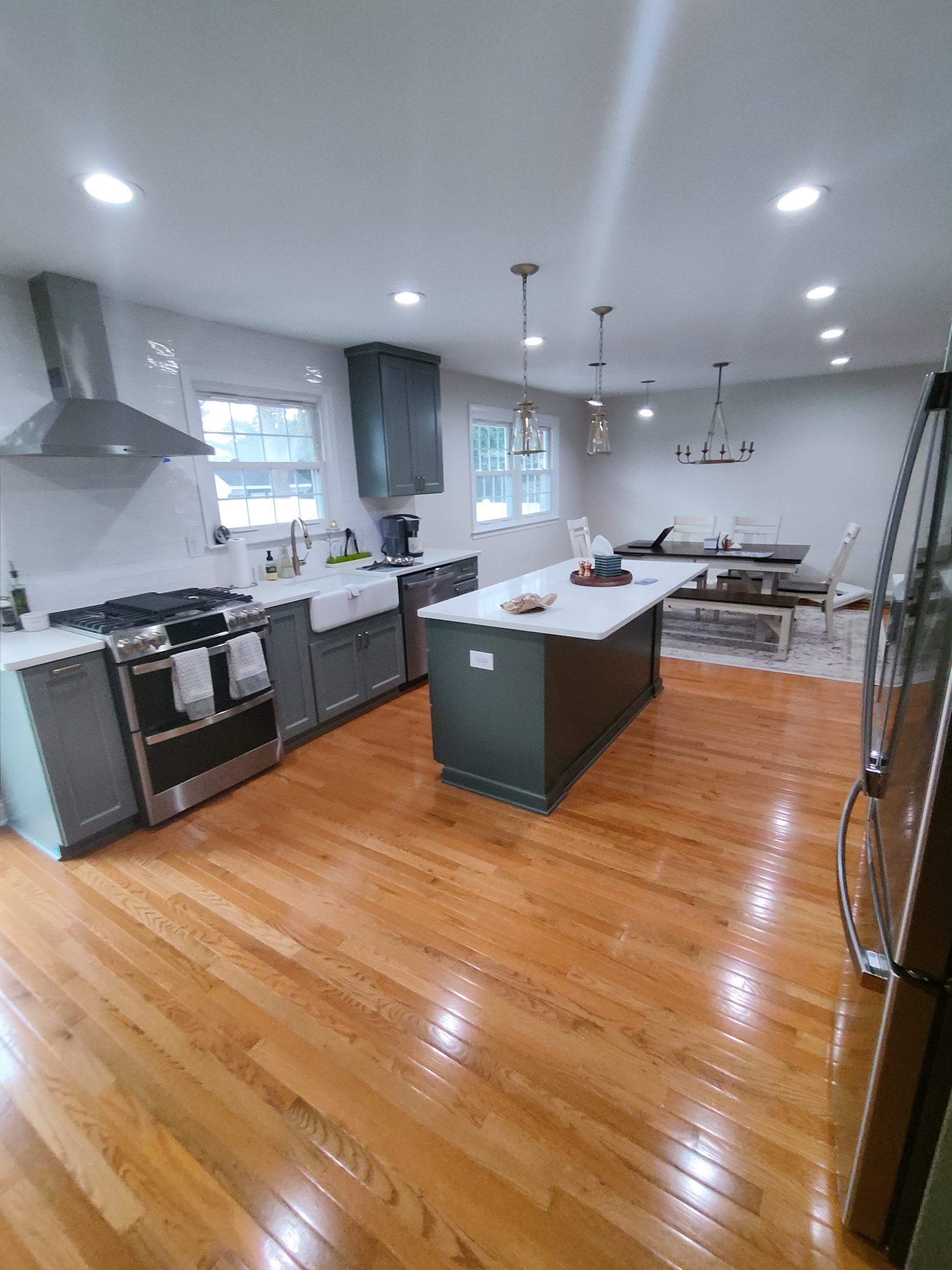 Modern kitchen with wooden floors, gray cabinets, white countertops, and an island.