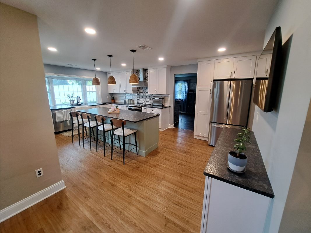 Kitchen with island, stainless steel appliances, white cabinets, and wood flooring.