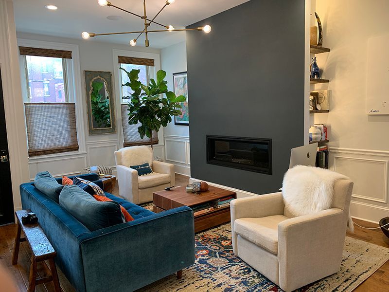 Living room with blue sofa, two cream armchairs, and a large fiddle leaf fig. Gray accent wall with fireplace.