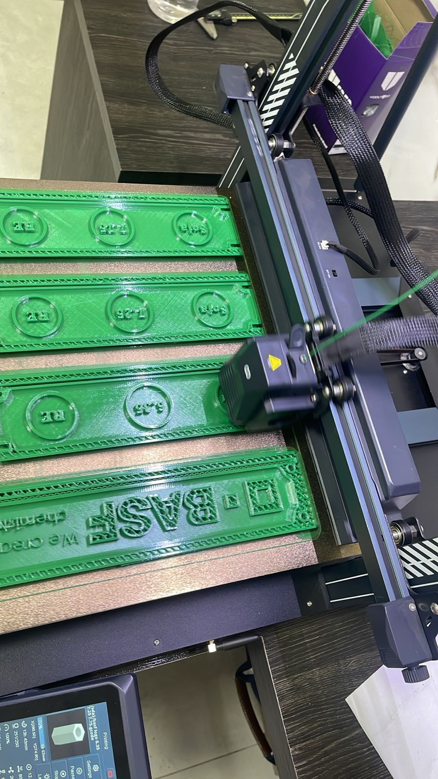 3D printer printing four green rectangle shapes 