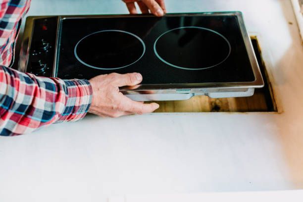 A man is installing a stove top oven in a kitchen. - Memphis, TN - Repair Squad Home Service