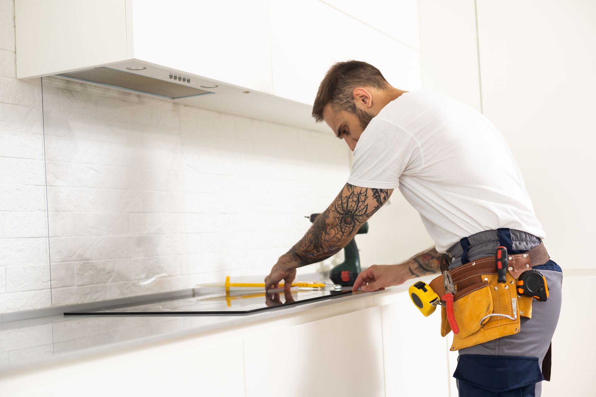 A man is working on a kitchen counter with a drill. - Memphis, TN - Repair Squad Home Service