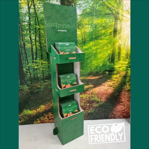 A green cardboard display stand with a forest in the background.