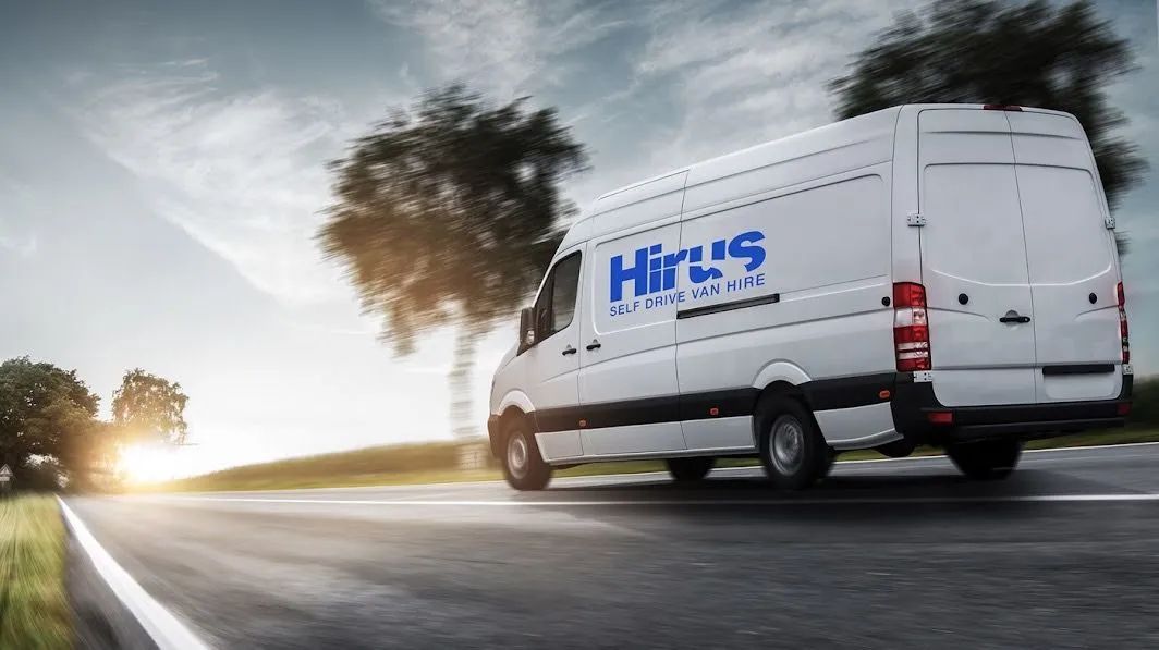 A white van with the word hirus on the side is driving down a road.