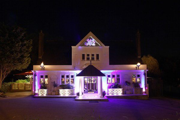 A large white building is lit up with purple lights at night