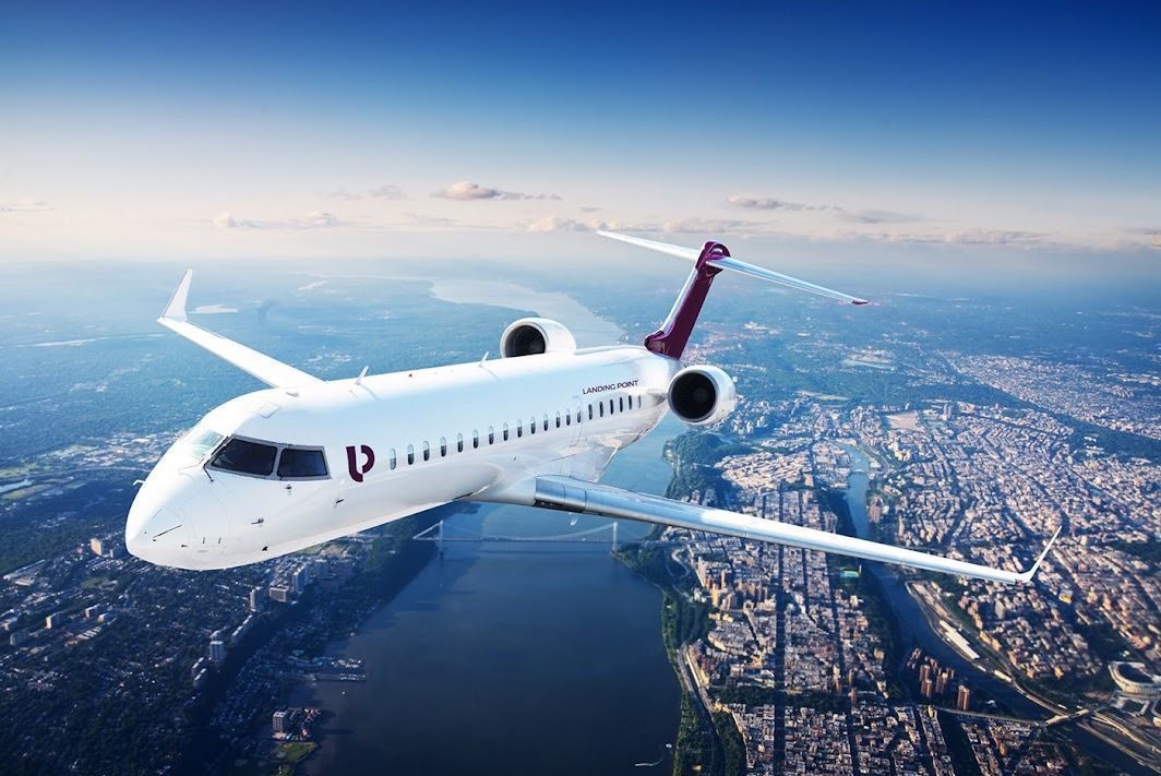 An airplane is flying over a city and a river.