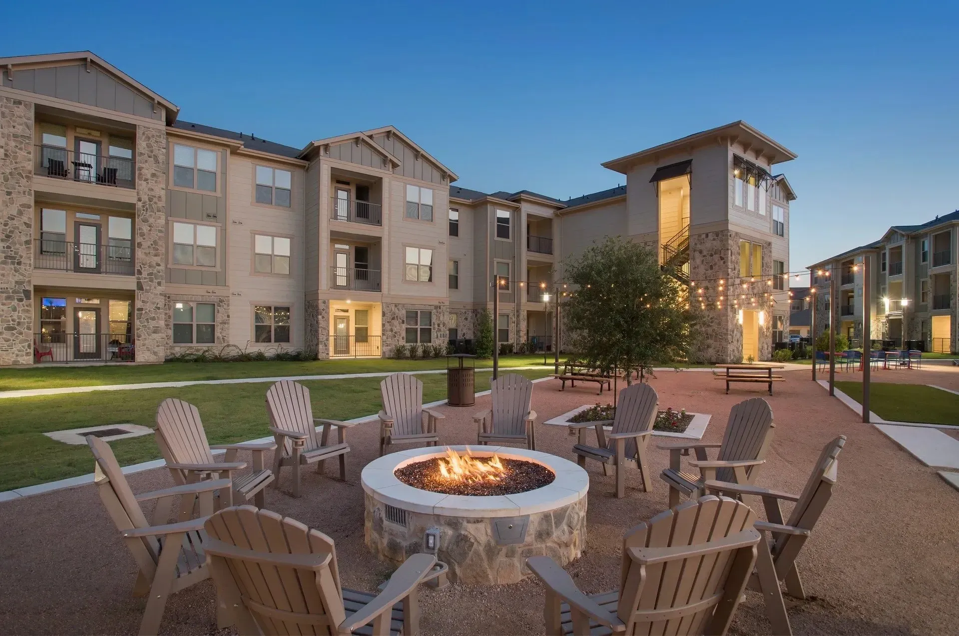 Outdoor fire pit area with seating surrounded by apartment buildings