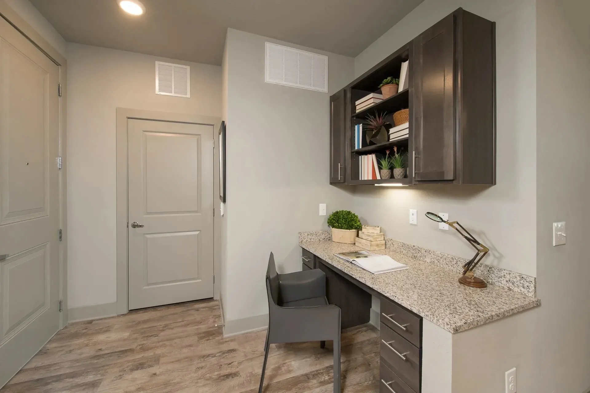 Interior view of a modern apartment workspace with a desk and shelf.