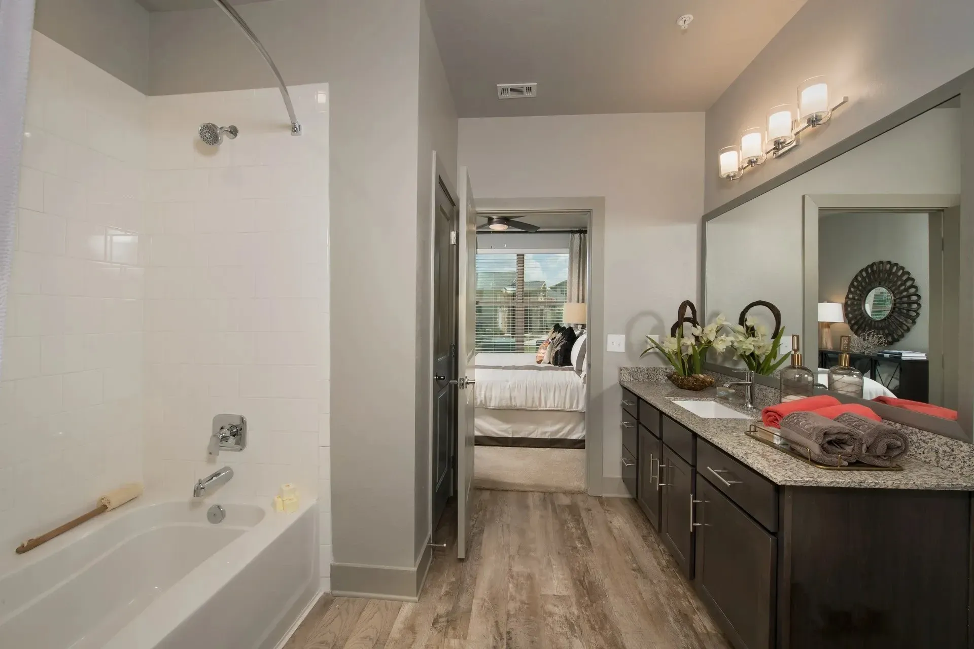 Modern bathroom with bathtub, dual vanity, and bedroom view