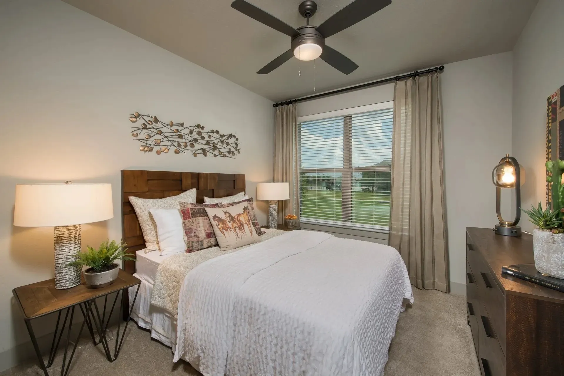 Cozy bedroom featuring a queen bed with decorative pillows and natural light from a window.
