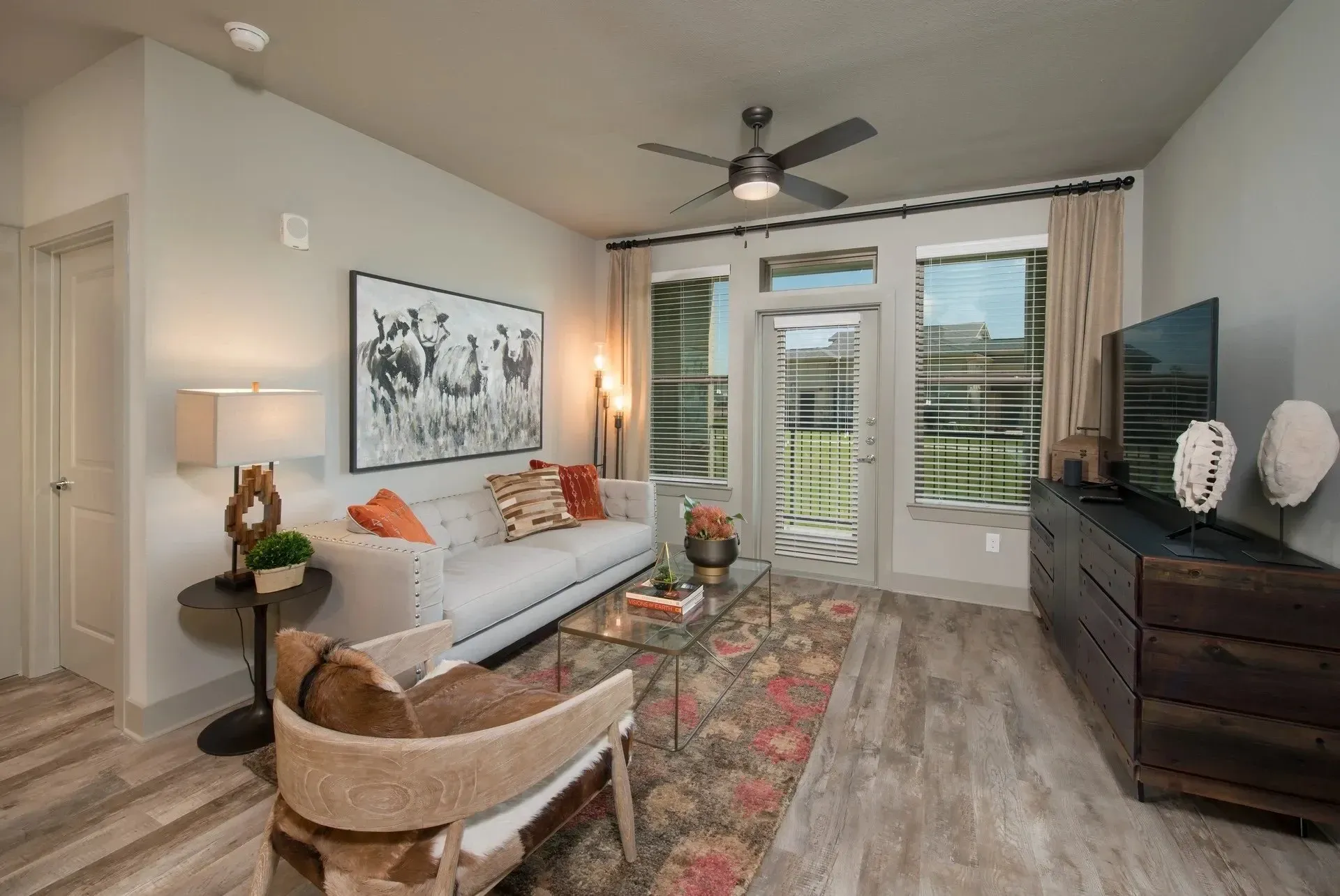 Modern living room with a sofa, glass coffee table, and large windows