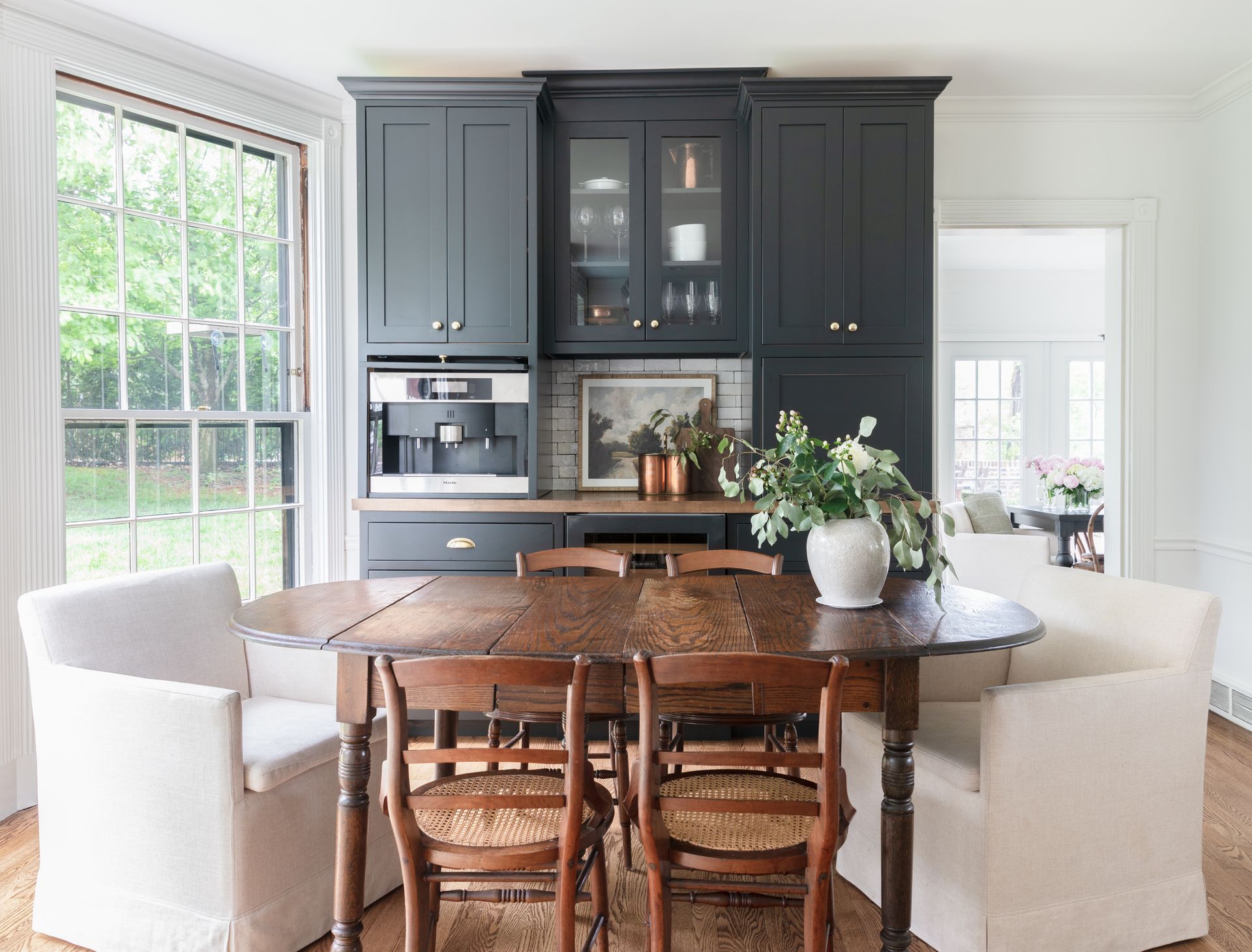 A dining room with a table and chairs and black cabinets.