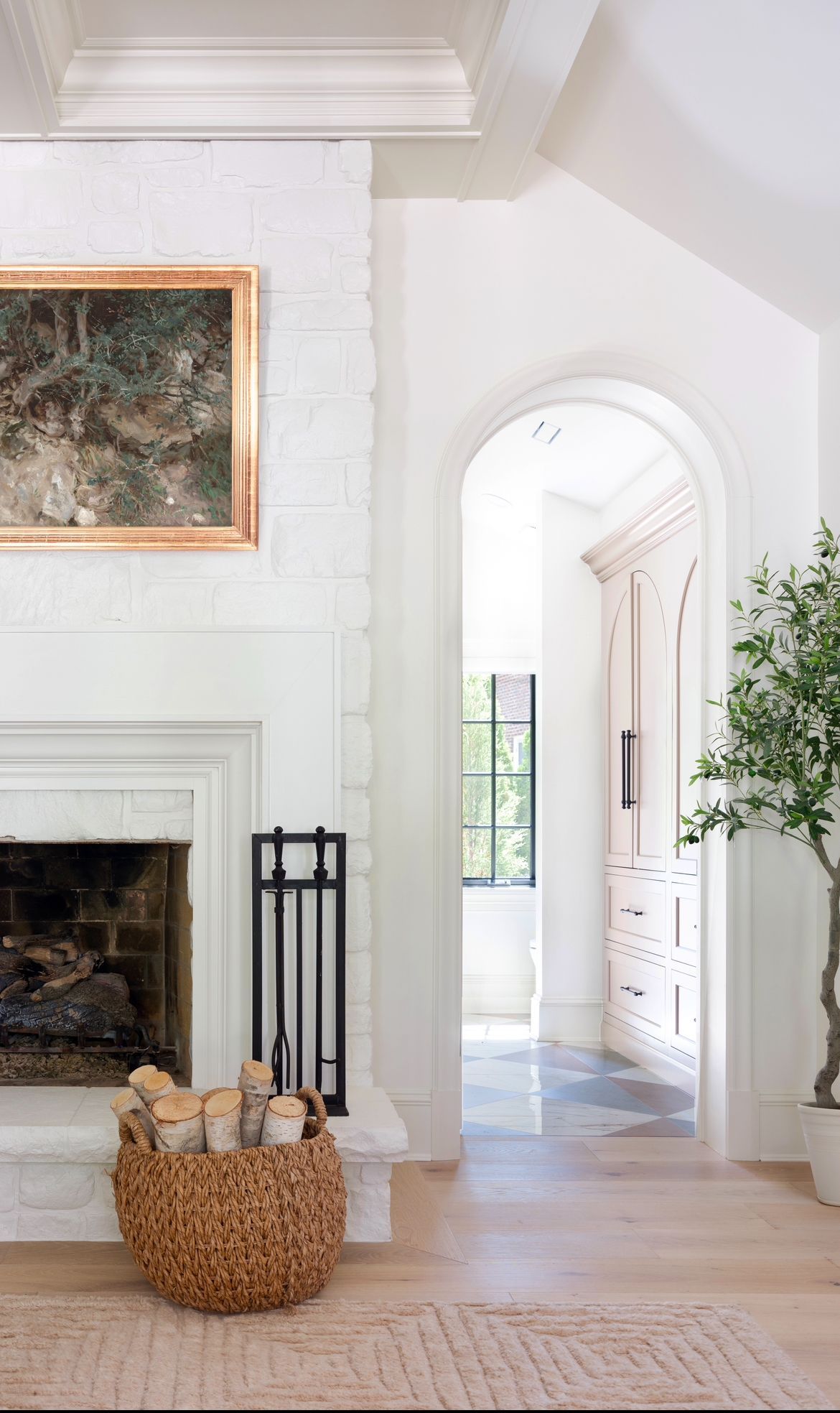 A living room with a fireplace and a basket of logs.