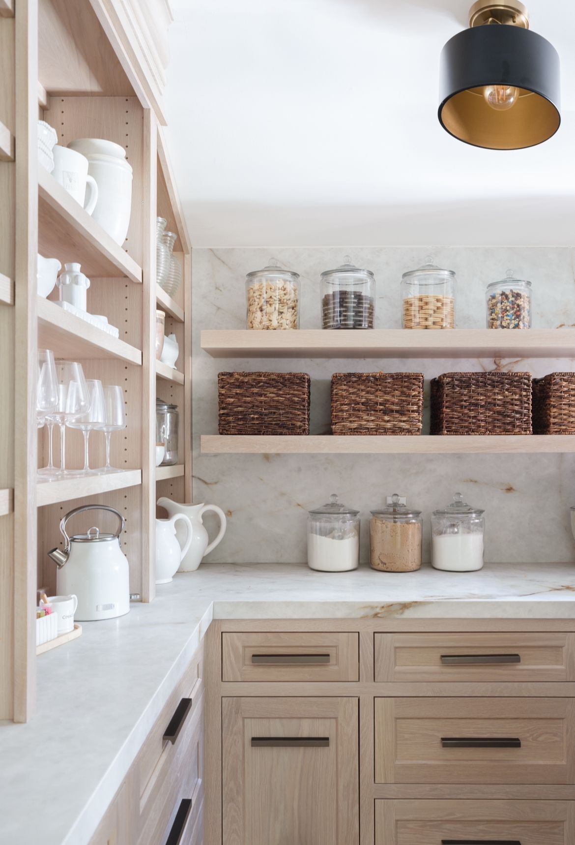 A kitchen with wooden cabinets and shelves filled with jars and baskets.