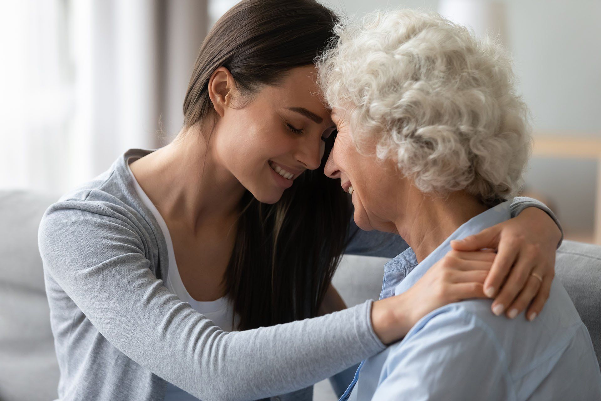 A young woman is hugging an older woman on a couch.