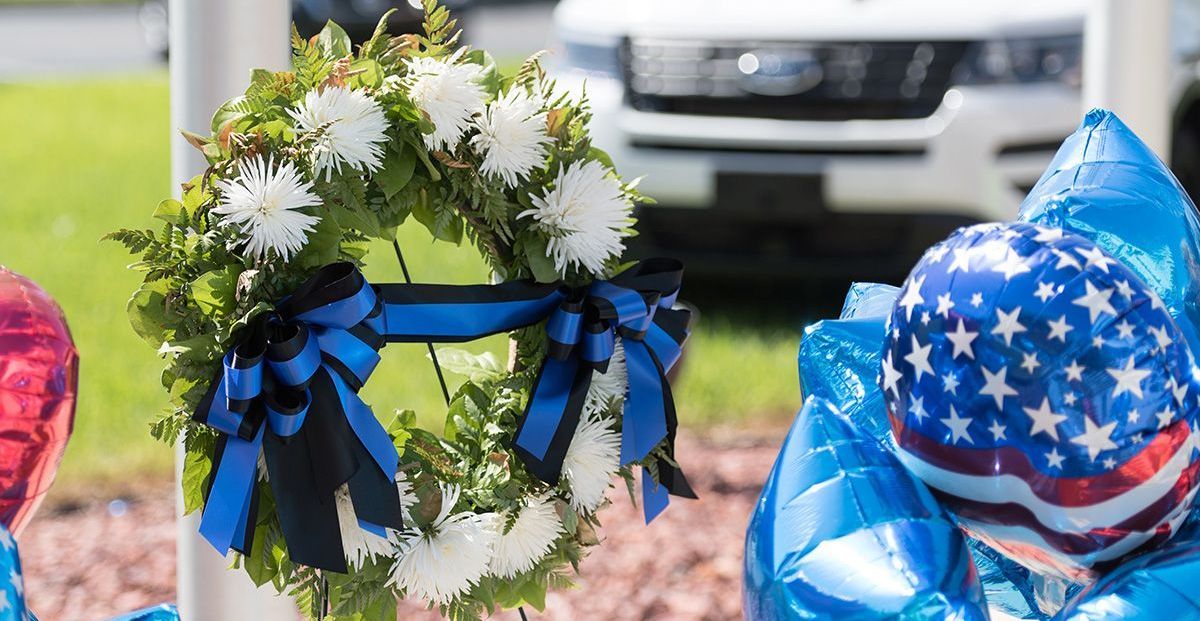 A wreath is sitting on a pole next to a blue balloon.