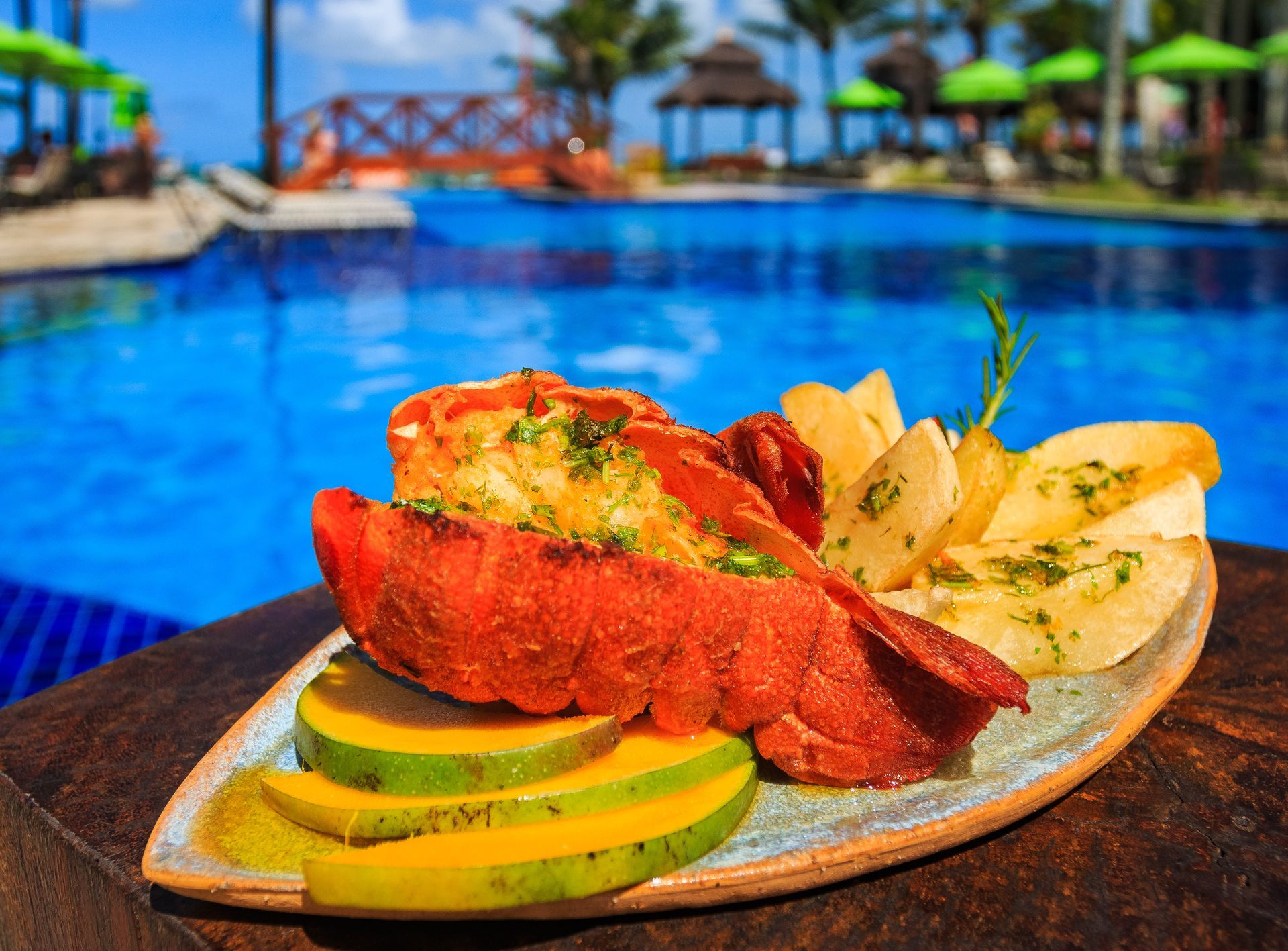 Um prato de comida está sobre uma mesa em frente a uma piscina.